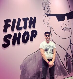 Seth Bogart Instagram - What an honor to design 3 collections of merchandise for the great new John Waters “Pope of Trash” show at @academymuseum ‼️
Seeing my art all huge on 2 walls at the end of the exhibit blew my mind. 

Love this pic @greggormanphoto took of John in front of my drawing of him. Just wait til you see the whole bathroom collection & the Divine/Pink Flamingos collection - both of those will be dropping sometime soon. Go see the show !!!