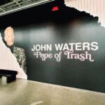 Seth Bogart Instagram - What an honor to design 3 collections of merchandise for the great new John Waters “Pope of Trash” show at @academymuseum ‼️ Seeing my art all huge on 2 walls at the end of the exhibit blew my mind. Love this pic @greggormanphoto took of John in front of my drawing of him. Just wait til you see the whole bathroom collection & the Divine/Pink Flamingos collection - both of those will be dropping sometime soon. Go see the show !!! Academy Museum of Motion Pictures
