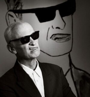 Seth Bogart Instagram - What an honor to design 3 collections of merchandise for the great new John Waters “Pope of Trash” show at @academymuseum ‼️
Seeing my art all huge on 2 walls at the end of the exhibit blew my mind. 

Love this pic @greggormanphoto took of John in front of my drawing of him. Just wait til you see the whole bathroom collection & the Divine/Pink Flamingos collection - both of those will be dropping sometime soon. Go see the show !!!