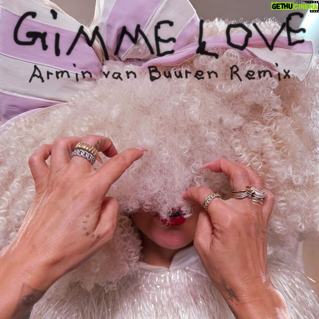 Sia Instagram - “Gimme Love” is getting the special remix treatment from @arminvanbuuren, out this Friday! 🦄🌈🎧 - Team Sia [image description: the cover of the Armin van Buuren remix of “Gimme Love” with Sia in a big, white wig and a white + pink bow]