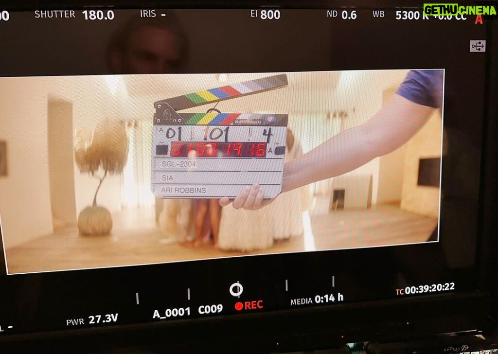 Sia Instagram - Counting down the days until the "Gimme Love" music video comes out... ⏱️ - Team Sia  [image description: a BTS pic of the "Gimme Love" music video with a clapperboard in front of a group of people in all white]