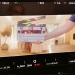 Sia Instagram - Counting down the days until the "Gimme Love" music video comes out... ⏱️ - Team Sia  [image description: a BTS pic of the "Gimme Love" music video with a clapperboard in front of a group of people in all white]