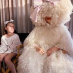 Sia Instagram - Waiting patiently ❣️ #GimmeLove - Team Sia [image description: a girl with a bow sitting next to Sia in a big white dress and white wig]