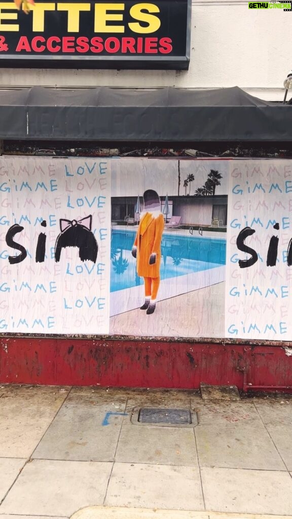 Sia Instagram - Spreading the love through LA! 🎬 Tag @siamusic if you see one in your city 💖 - Team Sia [video description: a person stepping over a Sia “Gimme Love” stencil on a sidewalk, panning up to posters of the “Gimme Love” and ‘Reasonable Woman’ art, set to the song “Gimme Love”]