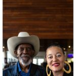 Stephen Hill Instagram – Deep Breath

Breathe writer/director @jamieburtonoare of @jomajafilms with one of her many proud family members who showed up for our premiere screening. Uncle Paul Haire.

Prior to our film block, I saw a beautiful film called Mosiah about Marcus Garvey. After that screening, I noticed Unc in his hat, in a sea of Garveyites proudly clad in Red Black and Green. I was able to meet him and share in the making of this photograph shortly after. 

Unc told me he inherited the hats of Grandaddy Eugene Henderson Burton, affectionately known as Doc. He said he switched his style up and started rocking the denim and cowboy boots to go with it. Now, he’s purchased a few more cowboy hats to go with the collection. We chuckled when I told him he had on what they call a Canadian suit/tuxedo. It was great to have him there and see how proud he is of Jamie.

Looking at this photo, I could talk all day about their beautiful brown faces anchoring and complimenting the mahogany wood backdrop or the balance between the weight of his hat and her earrings. But I find myself thinking of the etymology of the word Cowboy. It is said that black cow-HANDS were first derogatorily called cow-BOYS, and the name stuck. I’m also thinking I want to go riding. But most importantly, I’m thinking of how long after we stop breathing, even a single item endowed or imbued with our essence can connect, heal, and inspire those we leave behind for generations to come. We all live and breathe our allotment of that first breath. “The LORD God formed the man of dust from the ground and breathed into his nostrils the breath of life, and the man became a living creature” (Genesis 2:7) We breathe for those that no longer can. 

Aloha (Alo=face, Ha=breath)

Now take a deep breath and give thanks to all that breathes life into you.

✊🏿❤️🙏🏿

#stephenhillphotos #leicaphoto #breathefilm #ericgarner
#icanbreathe @detblackfilmfest #genesis27 John and Marlene Boll Family YMCA