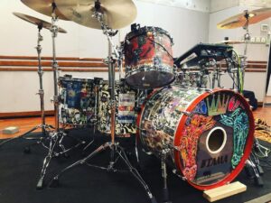 Yu Seki Instagram - 新しい相棒の紹介をします。
太鼓はTAMAのSTAR Walnut
Bass 24×17
Tom 13×11
Floor Tom 16×16、18×16
1Tom2Floorの王道ロックな構成で作っていただきました。
元々TAMAは太鼓はもちろん、ハードウェア類は特に使いやすくて耐久性もバッチリで好きでした。
愛知にあるTAMAの工場に伺った際、STAR Maple、Bubinga、Walnutの22インチのセットをそれぞれ試奏させていただきましたが、Walnutのファット且つ弾力のあるしなやかなローミドルが気に入り、オーダーさせていただく流れになりました。

そしてそんなSTAR WalnutをDWS(@dwsjapan )で渋く眩くヨゴしてもらいました。
マジで気に入ってる！！！
バスドラにはゆかりのある人物やKing Gnuとミレパの曲名の当て字やら歌詞やら俺の個人的な推しやらコータめんの個人的な思想等、千社札にしてくちゃくちゃに貼りまくってあって末永く楽しめそう。
身内にしか伝わらないであろう当て字とか青春っぽくて感動。

コータめん&かおるっちありがとう！
そしてエンドーサーの立場でありながら、ここまでのペイントを施すことを許していただいたTAMA(@official_tama_drums_japan )の深い懐に全身全霊の感謝を捧げます。

10/14からのツアー、このシブくてマブい相棒と駆け巡るんで、どうかよろしく。