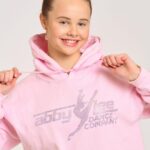 Abby Miller Instagram - The holidays are right around the corner and the Abby Lee Dance Company has you covered! Head over to store.abbyleedancecompany.com or in person @aldcstudiola for some amazing merch including this super cute baby pink rhinestone hoodie 🎀 Los Angeles, California