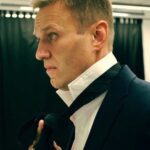 Alexey Navalny Instagram - Я смеюсь минимум три раза в день, даже когда совсем один в камере. Всё дело в музыке. Я начал из-за нее ругаться. В каждой камере стоит радиоточка. И с утра до вечера включены кошмарные радиостанции, где постоянно Газманов. Ну я и начал требовать, чтоб хотя бы на пару часов в день включали «Европу плюс». Когда я что-то требую, тюремщики — ясное дело — поступают ровно наоборот. Например, просил увеличить время, на которое мне дают ручку и бумагу (было 1,5 часа в день), — мне сделали 35 минут. И с музыкой так же вышло. После моей просьбы всему ШИЗО/ПКТ вообще вырубили музыкальные радиостанции и оставили только новостную — «Радио России». 24 часа вранья и рекламы лекарств. Но это еще не всё! Что сделает работник ФСИН, если захочет насолить с помощью музыки? Правильно! Включит классическую. Ведь он считает, что это пытки и наказание. И вот теперь во время завтрака, обеда и ужина в камерах играет классическая музыка. Я совсем не ценитель, но норм, могу послушать. Но только вот одно из проигрываемых произведений максимально мрачное и похоже на похоронный марш. А ещё, когда баландер даёт еду в камеру через кормушку в двери, он кладёт кусок хлеба на кружку, ну чтобы хлеб ни до чего не дотрагивался. Но выглядит это похожим на то, как на поминках кладут кусок хлеба на рюмку с водкой. А ещё тут часто дают какое-то подобие рисовой каши, что похоже на традиционное поминальное русское блюдо — кутью. И вот я сижу в камере за столом в своём чёрном зековском костюме, ем поминальную кутью, рядом кружка, накрытая хлебом, и играет похоронная музыка. В этот момент я представляю, что в Твиттер или Инстаграм идет прямая трансляция происходящего и вы видите всё это. Я не выдерживаю и начинаю смеяться. Самый весёлый человек на поминках 😉