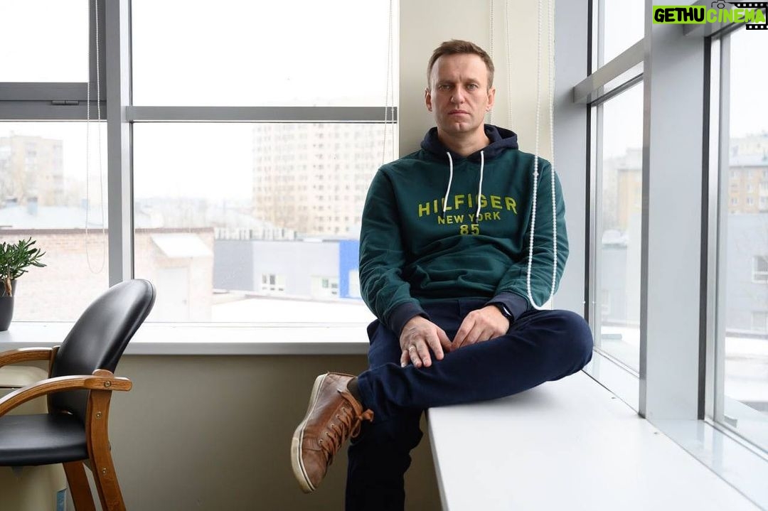Alexey Navalny Instagram - Я - икона осознанного потребления. В моей камере есть только кружка и книга. Ложку и тарелку дают на время еды. И даже тюремную мою одежду забрали, выдав временную. Теперь на моей спине огромные белые буквы: ШИЗО. Всем привет из штрафного изолятора. Настоящая профсоюзная борьба никогда не бывает легкой, чего уж говорить о профсоюзе в тюрьме. Кремль хочет видеть свой ГУЛАГ состоящим из безмолвных рабов. А тут я вместо того, чтобы умолять о помиловании, кого-то объединяю и требую соблюдения каких-то законов. Поэтому меня вызвали из барака на комиссию, где объявили, что на видеозаписях видно: я, находясь на промзоне, регулярно расстегиваю верхнюю пуговицу робы. Это, безусловно, характеризует меня как неисправимого злодея. Поэтому принято решение водворить меня в штрафной изолятор. Пока на 3 суток, но - радостно улыбнулся и.о. начальника, - в середине сентября у меня свидание с родственниками. Содержащимся в ШИЗО свидания запрещены, поэтому если я “не пересмотрю свое отношение”, то изолятор станет моей постоянной резиденцией. Непонятно, отношение к чему я должен пересмотреть. К рабскому труду? К Путину? ШИЗО - самое суровое наказание в легальной тюремной иерархии. Впрочем, в нелегальной тоже - пытают и убивают чаще всего именно здесь. Устроено это так. Бетонная конура 2,5х3 метра. Чаще всего там невыносимо, потому что холодно и сыро. У меня пляжный вариант - очень жарко и почти нет воздуха. Форточка крохотная. Вентиляции нет. Ночью лежишь и чувствуешь себя рыбой на берегу. Железная койка пристегивается к стене. В 5 утра забирают матрас и подушку (это называется “мягкий инвентарь”) и поднимают койку. В 9 вечера койку снова опускают. Железный стол и лавка, раковина, дырка в полу. Под потолком две камеры. Свидания запрещены, письма запрещены, передачи запрещены. Единственное место в тюрьме, где даже курение запрещено. Бумагу и ручку дают на 1 час 15 минут в день. Прогулка - час в такой же камере, но с куском неба. Все время обыски и руки за спиной. Вот сижу сейчас на железной лавке за железным столом. Допишу этот пост и буду писать инструкцию для зэков об их правах на рабочем месте, пока не заберут бумагу. Права комиссия: кажется, я неисправим 😉