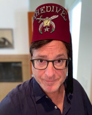 Bob Saget Instagram - Okay, why am I wearing a Fez? Well for the first time ever, since my dad left us for greater pastures, I went through some of his stuff and found some of his treasured accoutrements— He was a very proud Shriner and 32nd degree Mason. For those that know, the Shriners are a society of people who do a lot of philanthropic work and often pay for surgeries for people that don’t have insurance and can’t afford medical care – – For kids and others who’ve needed organs, major super expensive surgeries, and they’ve saved many lives. I just wonder if you have to wear this Fez to do all that. By the way, it is in mint condition. That was my dad, and incredibly kind, smart, and caring man. I wonder if he ever wore this hat.