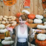 Bryce Dallas Howard Instagram - Hey, October 😉🍂⁣⁣ ⁣⁣ 📸: @andiejjane⁣⁣ ⁣⁣ [ID: BDH playfully poses in front of a display at @traderjoes with pumpkins of all different shapes, sizes, and colors. In full autumn vibes, she wears navy blue jeans, a white t-shirt, and a beige and brown cardigan. 3 smiling scarecrows hang on the wall in the back.]⁣