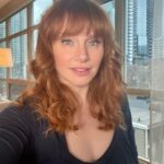 Bryce Dallas Howard Instagram – Views from beautiful, magical Toronto — it’s beginning to feel a lot like the holiday season ❤️ ⁣
⁣
[ID: Wearing a navy-blue blouse and her hair in curly waves, BDH takes a selfie by a window in her Toronto hotel room. Outside the window, the next morning, is a light dusting of snow across roof tops and trees.]