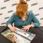 Bryce Dallas Howard Instagram - 8 hours of signatures later 😅 It means the world that fans across the movie multiverses want to memorialize these stories!! Thank you @swau_official for organizing such a fantastic signing day — my inner fangirl had the time of her life⁣ ⁣ and p.s. @missmistyrosas, @chrisfbartlett, @therealbrendanwayne, and @lateefcrowderdossantos: it’s always an honor to put my signature next to yours ❤️⁣ ⁣ [ID: BDH, wearing a linen teal button down blouse, smiles as she signs a Claire Dearing / Jurassic World poster]