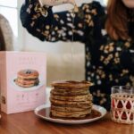 Bryce Dallas Howard Instagram - “Keep pouring,” they said 🤣 Upgrading my Sunday brunch game with @sweetlaurelbakery’s simple and delicious pancake mix 💕 Gluten-free, dairy-free, and paleo, there’s no going wrong here — place your order today at Sweet Laurel’s website in my bio:)⁣ ⁣ (not an ad, just a MASSIVE fan!)⁣ ⁣ [ID: BDH is living out her breakfast dreams as she pours a pitcher of syrup over a stack of Sweet Laurel pancakes. Smiling, she wears a navy dress with a peach and white floral pattern.]