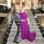 Bryce Dallas Howard Instagram – Joyful Moments with @jeffgoldblum: the B-side #JurassicWorldDominion ⁣
⁣
[ID: Candid photos of Jeff and BDH playfully posing on the steps of a grand staircase. Jeff wears an all black leather ensemble and BDH wears a plum floor-length gown.]