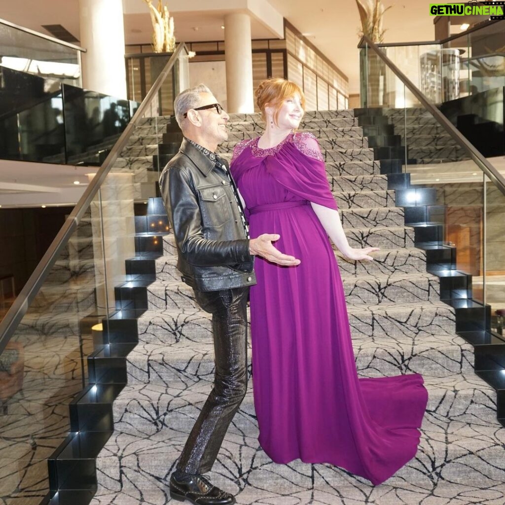 Bryce Dallas Howard Instagram - Joyful Moments with @jeffgoldblum: the B-side #JurassicWorldDominion ⁣ ⁣ [ID: Candid photos of Jeff and BDH playfully posing on the steps of a grand staircase. Jeff wears an all black leather ensemble and BDH wears a plum floor-length gown.]