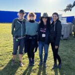 Bryce Dallas Howard Instagram – Filming on #InternationalWomensDay with these beauties was a BLAST! Plus, we wrapped early 😉⁣
⁣
[ID: As the sun sets behind tall blue screens on a grassy field, BDH smiles as she stands next to the 1st AD, DP, and Executive after a great day on set.]