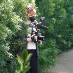 Bryce Dallas Howard Instagram – They say a director must become one with their environment 😉🌳 I’m filming my second documentary feature for @disneyplus and am very excited for you see what’s on the other side of the camera! ⁣
⁣
For all the film techies out there, this is @canonusa’s EOS C300 — I was so lucky to be one of the first directors to test this camera back in 2011 for my short film “When You Find Me” 🚀 I absolutely love how intuitive it is to operate. 100% recommended. ⁣
⁣
[ID: BDH in a grey cardigan, white v-neck, and black leggings becoming one with tall hedges, holding a Canon camera. 📸: @fullyjacked]