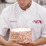 Buddy Valastro Instagram - A baking lesson with the @buddyvalastrojr_ as he perfects our delicious Vanilla Rainbow Cake! 🤩🌈🎂 Add some color to your day with our Rainbow Cakes! Visit carlosbakery.com today! 🚀💫 #carlosbakery #cakeboss #rainbowcake #cake #fatherandson
