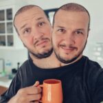 Şahan Gökbakar Instagram – Ozellikle ikinci dozdan 3 hafta sonra, beyincik soganimdan yeni bir filizlenme oldu. Once anten oldugunu ve artik 5g cekecegimi dusunup cok mutlu oldum.. ama sonra 2. Kafamin ciktigini farkettim. Başlarda  birbirimize hic alisamadik. Surekli iki bogaz doyurmak, cift maske takmak ve sosyal mesafeyi korumak vs. cok zordu. Ama bu surec bana hayata bakarken “BEN” degil “BIZ” diyebilmeyi ogretti…Kuresel gucler hucre cekirdegimi bozup beni iki kafali etseler de, ayaga kalkmayi tekrar hayata tutunmayi basardim. Ileride baska uzuvlarimda cogalabilir, hazirim!! Ve Evet..!! Artik ben ve Spike (ismi spike)  daha mutluyuz. Tesekkurler Bill Gates ve kuresel dostlari… oyun boyle bozulur!