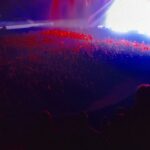 Danila Poperechny Instagram - Отработал 2 стадионных концерта: в Дубае и Вильнюсе. Идентичный материал, который я читал уже больше 30 раз, не считая сколько он обкатывался по частям на оупенах. И эти два концерта стали для меня отличным примером того, насколько же иногда по разному заходит один текст на разную аудиторию. Казалось бы - понятная истина для любого человека, но как же сложно порой бывает принять это, когда ты "автор произведения". Не сказал бы, что с концертом в Дубае было что-то не так - он был норм. Но вот именно, что "норм". Так вышло, что он был одним из тех, на котором часть материала просто "не попадала" в некоторую публику, из-за чего на выступлении постоянно было ощущение, что нам всем не удается запрыгнуть на одну волну. Например я видел, как из зала несколько раз вставали и уходили люди, как только начинали звучать блоки, безотказно работающие в других залах до этого. Уходящих было совсем не много и уходили они под звуки смеха остального зала, но они были и я естественно их замечал. Обычно, после подобного я провожу работу над ошибками, пытаясь понять, что же я сделал не так. Не так подал, не с теми интонациями говорил шутки, не достаточно расположил зрителя в начале, забыл какие-то важные блоки, может был слишком уставший на сцене, возможно материал устарел и тд. Но в этот раз я решил абсолютно ничего не менять и провести концерт в Вильнюсе точь в точь, как в Дубае, чтобы проверить, в чем же было дело. Я так и сделал, и, к моему сюрпризу, выступление прошло просто потрясающе. Большой стадион в полторы тысячи человек, который был еще больше, чем зал в Дубае - реагировал гораздо вовлеченнее, громче и теплее на те же самые вещи, которые вообще не вызывали отклика у некоторых дубайских зрителей. Единственный поинт, который хотелось сегодня высказать - рефлексия это, конечно, хорошо. Людям, которые создают что-то, жизненноважно находиться в постоянном самоосмыслении и анализе того, как становиться лучше. И это правильно, потому что неудачи будут преследовать вас на пути регулярно, и нет ничего важнее чем то, чтобы вынести из них как можно больше опыта. Но не забывайте, что иногда все дело может быть в том, что "в зале просто не совсем ваша публика". 📷@makslonglive