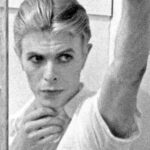 David Bowie Instagram – Please forgive the graininess of our latest Bowie Reflection. It’s an enlargement of TJ Newton (Bowie) on the set of The Man Who Fell To Earth, taken by David James. 

Here’s the caption from the reverse of the uncropped photo: “Mary-Lou (CANDY CLARK) tries to break down formal barriers between herself and Thomas Jerome Newton (DAVID BOWIE) when she invites him into her bathroom.”

The second image is of Bowie’s original artwork (see signature bottom right), a collage he created utilising two other stills from the same scene.

If you’re unfamiliar with this piece, it first appeared as a full-page in the 1976 ISOLAR tour programme and it was also an exhibit at the David Bowie Is V&A exhibition. (See last image)

Look closely at Bowie’s reflection and the bubbles in the bath. A bit of pre-Photoshop scalpel work by Bowie.

Thankfully, his replacement of the bubbles with Linoleum keeps us on the right side of social platform censors. The original image of Mary Lou was a little more revealing. 

#BowieReflections