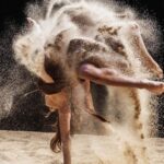 Derek Hough Instagram - BTS - “Turning Page” There are always challenges when bringing an idea to life. We wanted to use the rotating platform to represent time. The changing and ever evolving nature of our lives. But on the day there was a problem. We wanted to add sand to better tell the story of impermanence of our time on this earth. And also cause it looks cool. But by adding 2,000 pounds of sand , the platform had issues rotating properly. We also found ourselves sliding off if it got too fast. Speaking of time, we were running out of it. As much as we planned and prepared , there were numerous technical issues, and problems we had to solve quickly in order to complete the vision. That’s the pain but also the joy in creating. It’s those moments when we come together and problem solve on the fly , collaborate with one another, motivate each other to keep moving forward to get it done.