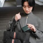 Dori Sakurada Instagram - Paul Smith 春の新⽣活に向けてぴったりのバッグ！ ポール・スミスのシグネチャーストライプ トートバッグ🌈 ナイロンジャカードで軽量さと耐久性があり、フロントのシグネチャーストライプのウェビングテープとファスナーポケットが素敵なアクセントになっています✨ レザーや⾦具はブラックで統⼀されているので、カジュアルな⽇も、スーツのセットアップなどにも合いそうです！ 開⼝部もファスナーが付いているので普段使いでも安⼼感があります✨ そしてそこにポール・スミスの幸運のシンボルでもある、ラビットモチーフをポイントにした3つ折り財布『マーケトリーストライプラビット』を組み合わせました！ ソフトでしなやかなイタリアンレザーが使⽤されていて、シンプルなベースにラビットがワンポイントで⼊っていて可愛いです🐇 どちらも新⽣活に⼼強いおすすめのアイテムになっています✨ 収納が多めのバッグが⼤好きなので僕もこれからの季節、撮影も始まるのでこのトートバッグをデイリー使いします！ @paulsmithjapan #PR #paulsmith #新生活 #paulsmithgifts