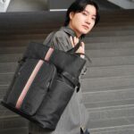 Dori Sakurada Instagram - Paul Smith 春の新⽣活に向けてぴったりのバッグ！ ポール・スミスのシグネチャーストライプ トートバッグ🌈 ナイロンジャカードで軽量さと耐久性があり、フロントのシグネチャーストライプのウェビングテープとファスナーポケットが素敵なアクセントになっています✨ レザーや⾦具はブラックで統⼀されているので、カジュアルな⽇も、スーツのセットアップなどにも合いそうです！ 開⼝部もファスナーが付いているので普段使いでも安⼼感があります✨ そしてそこにポール・スミスの幸運のシンボルでもある、ラビットモチーフをポイントにした3つ折り財布『マーケトリーストライプラビット』を組み合わせました！ ソフトでしなやかなイタリアンレザーが使⽤されていて、シンプルなベースにラビットがワンポイントで⼊っていて可愛いです🐇 どちらも新⽣活に⼼強いおすすめのアイテムになっています✨ 収納が多めのバッグが⼤好きなので僕もこれからの季節、撮影も始まるのでこのトートバッグをデイリー使いします！ @paulsmithjapan #PR #paulsmith #新生活 #paulsmithgifts