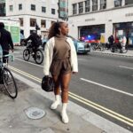 Jackie Aina Instagram - where we going? 💭 🗺️ (swipe to the end to find out) coat: #dior cardigan: #dissh shorts: #jacquemus boots: Dior handbag: #bottega earrings: Dior #londonstreetstyle #londonfashion Hermes New Bond Street