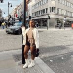 Jackie Aina Instagram - where we going? 💭 🗺️ (swipe to the end to find out) coat: #dior cardigan: #dissh shorts: #jacquemus boots: Dior handbag: #bottega earrings: Dior #londonstreetstyle #londonfashion Hermes New Bond Street