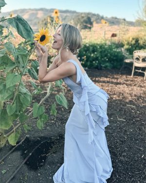 Julianne Hough Instagram - A few of my favorite things… sunflowers and a beautiful @victoriabeckham dress 🌻💜

Sunflowers are some of the most magical flowers I’ve come across, which is why they’re my favorite. They always turn to face the sun and they’re known as a symbol for hope, healing and joy - something I always strive to have in my life and surround myself with. Even named my little one Sunny ☀️🐶