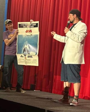 Kevin Smith Instagram - The Jersey Girl came to see JERSEY GIRL! @raquelxcastro paid a visit to my beloved @smodcastlecinemas to cap off a Memorial Day weekend full of shows! On Friday, we showed JAWS as part of the Movies That Made Me series. Then on Saturday night, we watched my flick RED STATE. But Sunday saw a reunion with the little girl who, at age 7, preternaturally played the role of Gertie in my sixth flick. We screened what we were calling JERSEY GIRL: The Snyder Cut, because it was the longest version of the flick ever edited, with an entire first act full of @jlo that got cut out due to post-Gigli hysteria. I haven’t seen any cut of JG since 2006, so it was a trip to see the movie I originally made #bennifer two decades ago. Hopefully, @paramountplus will want to stream it in 2024 for the 20th anniversary. It’s almost an entirely different flick. Also entirely different: Raquel, who’s now about 2 years younger than her cinematic Dad #benaffleck was when we shot it. I was happy to discover our troubled film didn’t ruin Rocky, who grew up to be such a wonderful kid with a great head on her shoulders. I can’t thank her enough for a killer kid performance, as well as for making the trip all the way from L.A. to be at #smodcastle with an ardent audience. It was a lovely weekend (with 3 profitable pre-show auctions, thank you bidders), during which I got to wear a trio of different jackets, as well as my new Smodcastle sneakers made by @1craftypunk! Next up: BABBLE-ON this Saturday and WATCH WITH KEV: @dctheflash on June 15, 16 & 17! Tickets available now at SmodcastleCinemas dot com! Take a trip to Smodcastle, where the movies come to play! #KevinSmith #smodcastlecinemas #raquelcastro #jersey #newjersey #film