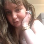 Lena Dunham Instagram – Hello from the floor of quarantine in London, where I am in full isolation in accordance with Tier 4 lockdown laws! But the chance to be alone with only a bag of crisps and my thoughts before I go full bore into the most ambitious project of my career has been a special lil’ gift- it’s given me a moment to reflect on the strength and stability I feel as I barrel toward my *official* mid-thirties, and how deeply it contrasts with the flightiness and fragility of my twenties. And it’s funny, because my twenties were much flashier- more outward facing achievement, more dresses and liquid eyeliner and taking my shoes off at parties and being told I was doing a hot job. But I was fighting my ass off to stay in the mix, for fear of what a moment of quiet might reveal to me- the roaring in my ears, the scraping in my brain. The last three years- since Girls ended, since my health and long term relationship collapsed at once and I had to rebuild myself in a new body and home, since I got sober and learned what it meant to really sit with myself- have been deafeningly quiet. But in that silence, more has occurred than ever did when I was dancing as fast as I could. I’ve discovered my own values. I’ve taken up dorky hobbies. I’ve built and scrapped and replotted dreams. I’ve healed without even knowing it was happening. I’ve planted the seeds for the kind of life I thought I was living but I was only playing at before- one full of art and friendship and honesty and love. I’ve motored my own boat (that… sounded wrong?) I guess this post is a glowing recommendation for quiet, in all its forms. It’s the opposite of boring. What’s boring is staying at the party too long. What’s cool is sitting in the bathtub afterwards. What have you found in the silence lately? London, United Kingdom