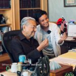 Mahathir Mohamad Instagram - Saya ditemuramah Umar Amirul Shakur Haiccal untuk satu rancangan di YouTube. Umar baru berusia 12 tahun dan minat bolasepak. Tanya Umar, macam mana nak capai umur 97 tahun. Saya jawab kena tunggu lagi 85 tahun lagi lah baru tahu macam mana boleh capai. Dalam temuramah tadi, saya cukup seronok dengar celoteh Umar dan dia begitu petah bercakap. Banyaklah soalan ditanya umpamanya bagaimana saya di zaman bersekolah, apa pesanan ibu saya, kenapa bina KLCC, Putrajaya, KLIA, pandangan bolehkah jadi influencer saja tanpa belajar dan banyak lagi. Umar tanya saya, kenapa ada helmet Star Wars dalam pejabat saya - The Mandalorian dan Darth Vader. Sebenarnya helmet ini dicetak mengguna 3D-printer. Saya berminat dan beli printer ini untuk buat sendiri beberapa barang, cumanya perlu belajar program dan sabar tunggu hingga siap. Kalau dahulu saya ukir kayu guna pisau dan tangan, sekarang semuanya pakai mesin. Lebih mudah. Cuma perlu faham dan mahir untuk program mesin saja. Semasa bergambar di hujung temuramah, Umar minta posing dengan “mini love”. Sengaja saya usik minta jelaskan apa itu “mini love”. Yang saya faham, rapatkan ibu jari dan jari telunjuk tu itu simbol minta duit! Umar terangkan simbol love asalnya besar, kena guna dua tangan untuk cantum jadikan love, tapi ada orang cipta pula simbol love dengan dua jari. Pandai dia menjawab. Saya pesan kepada Umar, rajin-rajinlah belajar supaya masa depan lebih terjamin. Semoga impiannya tercapai suatu hari nanti. InsyaAllah. Perdana Leadership Foundation
