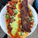 Mark Wiens Instagram - Fully loaded “memela!” @mexi_papa_adventures @jeffrey_merrihue Essentially a huge masa base, topped with salsas, fresh Mexican cheese, al pastor, chorizo, guacamole, and a rib thrown on as a topping! #LosAngeles #MexicanFood #streetfood 📍 @tacos_a_cabron Tacos A Cabron