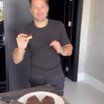 Mark Wright Instagram - VIRAL PEANUT BUTTER CHOC BARS. Had to try these and had to put my own twist on them. 🍫🥜☕ This is just one of the hundreds of recipes on our @_livewright_ coaching app. Signing up though means your entire meal plan gets tailored to you and your goals. So if you want to put on muscle or lose fat but you don’t like onions or you’re a vegan then we would build a plan around exactly that. INGREDIENTS: 2/3 cup peanut butter (melted) 1/2 cup honey 1 tsp coffee extract (could swap this for vanilla) 6 lightly salted rice cakes 100g dark choc (70% is great) 2 tsp coconut oil Flaky sea salt to top METHOD: 1. In a bowl, mix together the peanut butter, honey, and coffee extract until smooth. Crumble in the rice cakes and mix. 2. Line a cake tin with parchment paper and then use a spoon to press the rice cake mixture tightly into the pan, ensuring it’s evenly distributed. Place in freezer to set. 3. Melt the chocolate and coconut oil together (I did mine in a pyrex dish over a pan of boiling water) until smooth and glossy. 4. Remove the base from the freezer and pour the melted chocolate on top. Spread until it evenly coats the rice cake mixture. Sprinkle with flaky sea salt. Transfer back to the freezer for 30-40 mins, or until chocolate is set. I then added a bit more sea salt. Who’s making these?!