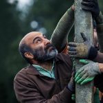 Mohsen Tanabande Instagram - جنگ جهانی سوم در راه است/درباره آخرین ساخته هومن سیدی، معرفی عوامل فیلم و انتشار اولین تصویر . فیلم سینمایی «جنگ جهانی سوم»، به نویسندگی هومن سیدی، آرین وزیردفتری و آزاد جعفریان و کارگردانی و تهیه‌کنندگی هومن سیدی این روزها در شمال کشور در حال فیلمبرداری است. این اولین تجربه تهیه‌کنندگی هومن سیدی است و محسن تنابنده، ندا جبرئیلی، مهسا حجازی، نوید نصرتی، لطف‌الله سیفی و حاتم مشمولی از جمله بازیگرانی هستند که در «جنگ جهانی سوم» به ایفای نقش پرداخته‌اند. این اولین حضور محسن تنابنده مقابل دوربین هومن سیدی است. در واقع تنابنده تنها بازیگر ستاره فیلم سیدی است که با یک بازی متفاوت در نقشی سخت به هنرنمایی پرداخته و سیدی مثل پروژه‌های دیگرش این بار هم سراغ یک سری چهره جدید و نوظهور رفته است. در خلاصه داستان این فیلم آمده «من همونی هستم که لباس تنت کرد، آدمت کرد، بهت بها داد، من همونم...» از عوامل اصلی که در این فیلم سینمایی هومن سیدی را همراهی می‌کنند می‌توان به حضور پیمان شادمان‌فر به عنوان مدیر فیلمبرداری، مهران ملکوتی، مدیر صدابرداری و محسن نصرالهی، طراح صحنه اشاره کرد که در واقع چندمین همکاری آن‌ها با هومن سیدی است. شادمان‌فر، ملکوتی و نصرالهی پیش از این در تولید فیلم‌هایی مانند «مغزهای کوچک زنگ‌زده»، «اعترافات ذهن خطرناک من» و همچنین سریال «قورباغه» سیدی را همراهی کرده‌اند. الهام معین به عنوان طراح لباس، فواد بوربور، مدیر تولید، مهدی صیاد، طراح گریم و حسین خضوعی، دستیار اول کارگردان، رسول حسینی، برنامه‌ریز، ایمان کرمیان، جلوه‌های ویژه میدانی، فرید ناصرفصیحی، جلوه‌های ویژه رایانه‌ای و امید صالحی به عنوان عکاس در این پروژه حضور دارند. «جنگ جهانی سوم» با سرمایه‌گذاری صددرصدی نماوا در حال تولید است و در واقع این اولین باری است که یک پلتفرم پخش آنلاین به ساخت یک پروژه سینمایی ورود کرده است. پیش از این پلتفرم‌ها تنها روی سریال‌هایی سرمایه‌گذاری می‌کردند که به صورت اختصاصی از آن‌ها پخش می‌شد اما حالا برای اولین بار نماوا تصمیم گرفته علاوه بر تولید سریال‌های اختصاصی در یک پروژه سینمایی هم ورود کند. «جنگ جهانی سوم» در واقع دومین همکاری نماوا با هومن سیدی پس از تجربه موفق «قورباغه» است. ‎عکاس: امید صالحی @namava_ir @houman_seyedi @mohsen.tanabandeh @paymanshadmanfar @nedajebreilii @omidsalehi.pix