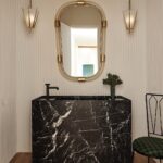 Nate Berkus Instagram - A perfect example where modern and vintage collide. In this desert project we used vintage lanterns suspended from the ceiling, a Murano glass and brass mirror from the 1960s and recovered a vintage iron chair in a black and green check to complement the new plaster walls and Nero Marquina black marble sink. Photographed by @jennapeffley for @archdigest #NateBerkusAssociates