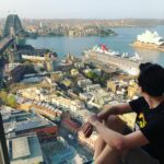 Phil Lester Instagram - I was sat at a window don’t worry I know I can’t be trusted with a precarious ledge I’m missing doing things today so I’m living though Phil of the past in my camera roll! Excited to get vaccinated and see a wild kangaroo again ..or maybe just go to the cinema either is cool Sydney Harbour