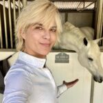 Selma Blair Instagram - This is my social life and it’s pretty grand. Mr Nibbles gives me all the emotions. 🎭 It’s getting hot out here, drink your water 💁🏼💦 Image Descriptions: Image 1: Selma has short blonde hair and wears a white long sleeve shirt. She is smiling and standing next to her white horse. Image 2: Selma wears a white long sleeve, tan pants, boots, and a helmet and is sitting outside. Video: Video of Selma riding her horse Image 3: Selma poses with her horse Image 4: Close up image of Selma in her riding gear. Image 5: Selma poses with her horse.