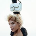 Selma Blair Instagram - It’s good to be back with the gang. Always love @marcjacobs. And our Stams. Image 1: Selma with short blonde hair, wearing all white clothes with white platform shoes, bends forward and holds a pink quilted bag. She is looking at the camera. Black text across the photo reads Marc Jacobs. Image 2: Selma with short blonde hair, wearing a black jacket, looks directly to the camera while holding a white bag over her head. Black text across the photo reads Marc Jacobs.