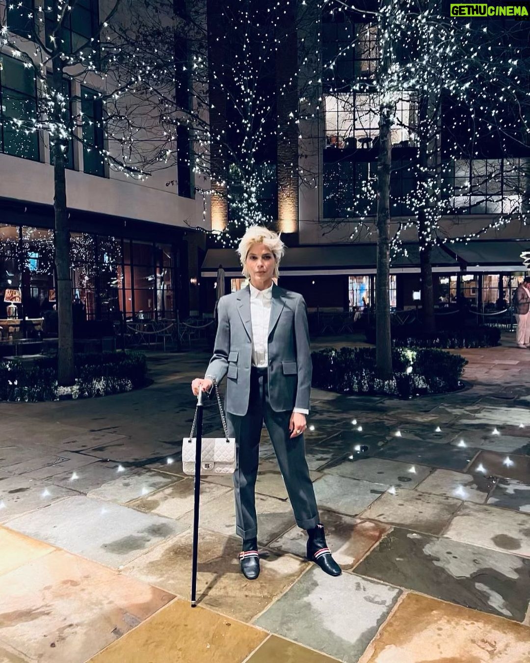 Selma Blair Instagram - London 🖤. It was time. We love you. I only wish I could stay longer. This time in London has been so good for my northern soul. And my son was enchanted as well. We met our dearest friends. Been too long. and I’m changed. Thank you Image descriptions: Image 1: Selma has short blonde hair and is standing with the London skyline behind her. Image 2: Selma and Arthur sit in separate chairs. Arthur has short brown hair and sitting on the left in a chair in a hotel lobby with black and white floor. Image 3: Silhouette of Selma holding her cane with a long coat on. Image 4: Arthur is on left wearing black jacket with a hoodie, hugging Stella, who is wearing long sleeve grey shirt. Image 5: Selma and Arthur walking to music that Stella, whose back is to the camera, plays on her phone. Image 6: Selma is standing with her cane next to Vanessa Kingori who is on the left wearing a light green outfit with her arm around Selma. Image 7: Selma is wearing a grey suit and holds her cane. She is standing outside, surrounded by lit up trees. Image 8: Selma is on the left kneeling with her cane in front of her next to Katie who has brown hair and is wearing glasses and wearing white boots. Image 9: Black and white photo of Selma with Anya Taylor Joy, who has long, straight blonde hair. Image 10: Video of Selma and Arthur walking on the street in London. London, England