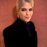 Selma Blair Instagram - The evening of Burberry. 🗡️ Image Descriptions: Image one: Selma has short blonde hair and wears a long black velvet coat. She is standing on the runway at the Burberry show with her cane with one hand in her pocket. Image two: Selma stands in front of orange wall. Image three: Selma sits with Edward and Naomi. Edward is wearing all black and Naomi is wearing a grey suit. Image four: Selma and Georgia are standing and both wearing black. Image five: Selma is standing in profile wearing a white robe while getting her hair done. Image six: Selma leans against an orange wall and is looking to the left.