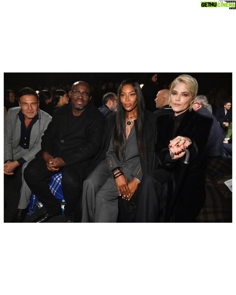 Selma Blair Instagram - The evening of Burberry. 🗡 Image Descriptions: Image one: Selma has short blonde hair and wears a long black velvet coat. She is standing on the runway at the Burberry show with her cane with one hand in her pocket. Image two: Selma stands in front of orange wall. Image three: Selma sits with Edward and Naomi. Edward is wearing all black and Naomi is wearing a grey suit. Image four: Selma and Georgia are standing and both wearing black. Image five: Selma is standing in profile wearing a white robe while getting her hair done. Image six: Selma leans against an orange wall and is looking to the left.
