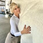 Selma Blair Instagram - I have the luxury of animals in my life. And this creature, has a playfulness and gorgeous energy that is nurtured everyday by my trainer at @cellardoorequestrian. When I have lost the plot, when I am treading water, my horse, Mr. Nibbles is a force greater than myself, grounding me here. When thoughts go haywire, when I lose my speech, holding onto this one clears my anxiety and loves me back. Thank you all creatures great and small. Image description: Image one: Selma has short blonde hair and is wearing a white long sleeve quarter zip top, tan pants, with a tan belt. She hugs her white horse, Mr. Nibbles while smiling at the camera. Image two: Selma has short blonde hair and is wearing a white long sleeve quarter zip top, tan pants, with a tan belt. She is giving Mr. Nibbles a kiss.