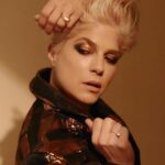 Selma Blair Instagram - Thank you @coveteur for highlighting my wellness journey 🤍 link in Stories Image 1: Selma has short blonde hair and is wearing a shiny black and bronze striped jacket. She has her hands lifted over head and face angled towards the camera, looking down. Her eye shadow is bronze and black. Image 2: Selma has short blonde hair and looks into a mirror as she holds a makeup tool for eyebrows from Guide Beauty Cosmetics. She wears a large emerald ring. Image 3: A headline from the Coveteur reads, “Selma Blair on Rediscovering Wellness Rituals That Work For Her.” Selma is quoted “now that I have cleared up some lost energy, I have the patience to witness my own imbalances.” Selma is shown sitting on a couch looking direct to camera.