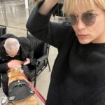 Selma Blair Instagram - 🤍🗽 Image Descriptions: 1. Selma has short blonde hair and is sitting on brick balcony wearing a grey coat with black collar. 2. Black/white photo of Selma and Christian Siriano at dinner. Christian has short dark hair and is wearing a black tshirt. 3. Selma is wearing a black sweater and sunglasses. A man is seated behind her playing with her dog Scout. 4. Black/white photo of Selma, Art Tavee and Carolyn Griffin at dinner. Art has short light hair and wears glasses and Carolyn has shoulder length hair. 5. Selma, Troy, Art, and Carolyn posing together for a selfie outside at dinner. 6. Selma posing in the mirror in a hotel bathroom. There are pink flowers in the focus of the photo. She wears a black sweater with a white collared shirt under it. New York, New York