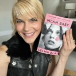 Selma Blair Instagram - Mean Baby is pretty in pink and paperback. 💞 Available tomorrow, May 9th. Image description: Selma has short blonde hair and wears a black top. Selma holds a paperback copy of her book, Mean Baby.