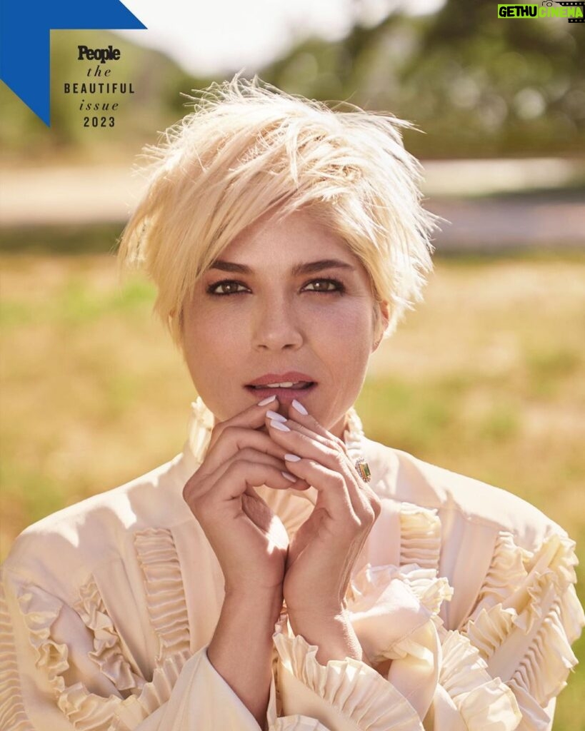 Selma Blair Instagram - “Good things will happen. And horrible things. And it will all be part of finding your footing and carrying on. You are worth loving.” To read more of my letter to my younger self, check out @people’s beautiful issue. Out now 💛 Image descriptions: Image 1: Selma has short blonde hair and wears a white blouse. Her hands are clasped in front of her mouth and she stands in a field of grass Image 2: Image of Selma as a young girl with long dark hair. She is smiling and wearing a black top with a white turtleneck under it. On the right is her sister Lizzie, who has long dark hair.